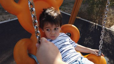 Sevimli küçük çocuk somurtkan yüzüyle salıncakta