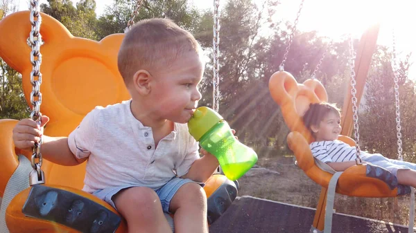 Hermanos balanceándose en el columpio en el parque —  Fotos de Stock