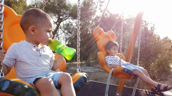 Hermanos balanceándose en el columpio en el parque — Foto de Stock