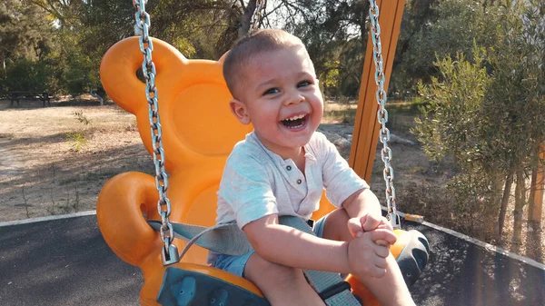 Adorable niño en un columpio con una gran sonrisa en su cara —  Fotos de Stock