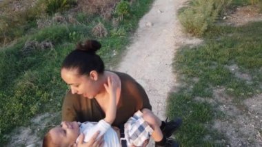 Genç anne bebeğini döndürürken, büyük çocuk uzak bir yere taş atıyor. Sonbaharda deniz kıyısında