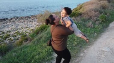 Genç anne bebeğini döndürüyor ve dilini kameraya doğru uzatıyor.