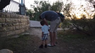 İki oğlu olan baba, bebeğinin yaralı dizini kontrol ediyor.