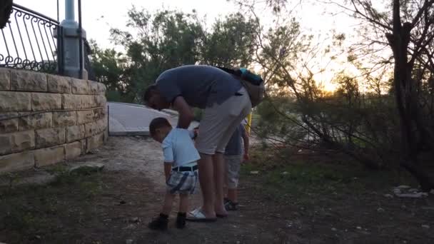Papa met twee zonen, kijkt naar de gekwetste knie van zijn zoontje — Stockvideo