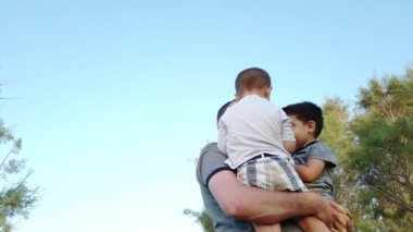 Mutlu, genç bir aile. Baba oğullarını doğada döndürüyor. Düşük açı