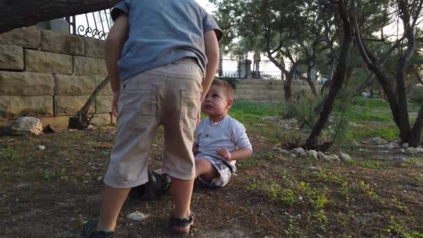 Lindo 4 años de edad ayudando a su hermano a limpiar la rodilla después de que se sintió abajo. Hermanos cuidándose unos a otros — Vídeos de Stock