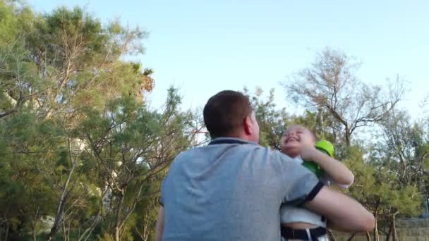 Gelukkige jonge familie. Vader tilt en spint zijn zonen in de natuur. Lage hoek — Stockvideo