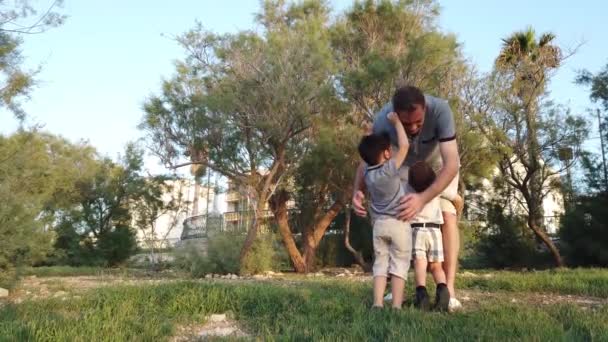 Il giovane padre che abbraccia i suoi figli nel parco. Concetto famiglia felice — Video Stock