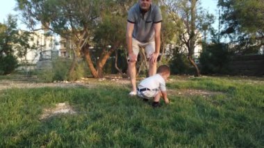 Sevimli çocuk çimenlikten su şişesini alıyor ve babası ona vuruyor. Aile bağı