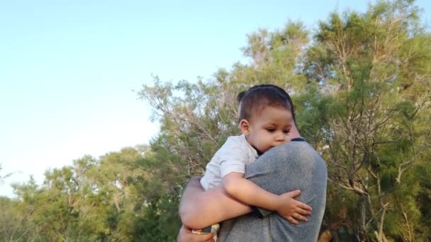 Молодий батько тримає свого сина-малюка. Дитина обіймає тата. — стокове відео
