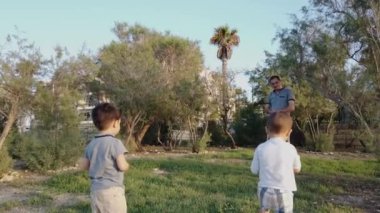 Baba ve oğulları parkta oynuyorlar.