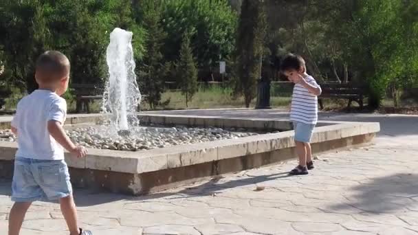 Roztomilí chlapci, sourozenci hrající si u fontány — Stock video