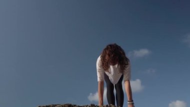 Yoga pozisyonundan kalkıp saçını düzelten genç bir kadın.