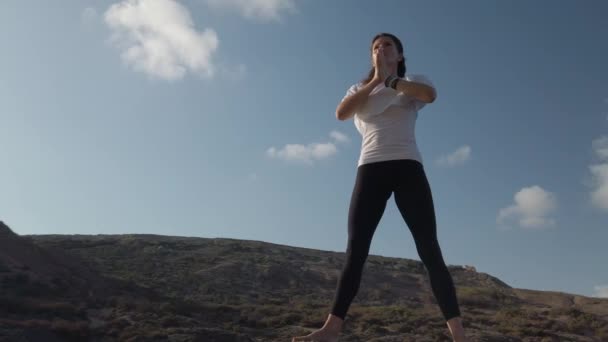 Mindfulness concept. jonge Kaukasische vrouw oefenen yoga op de rotsachtige strand — Stockvideo