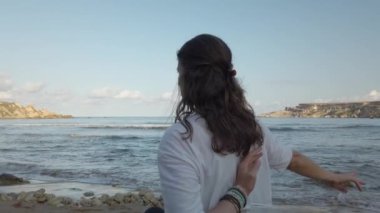 40 'lı yaşlarda bir kadın sabahın erken saatlerinde kumlu sahilde yoga yapıyor.