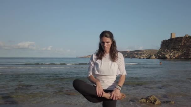 Ung kaukasisk kvinna, brunett gör yoga på stranden tidigt på hösten morgon — Stockvideo