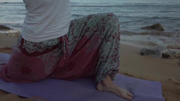 Låg vinkel. Ung kvinna som gör yoga, ashwa sanchaalanasana ridsport pose, på sandstrand på tidig morgon — Stockvideo