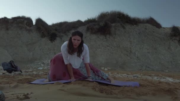 Mujer de 40 años practicando yoga en la playa de arena en la madrugada — Vídeo de stock