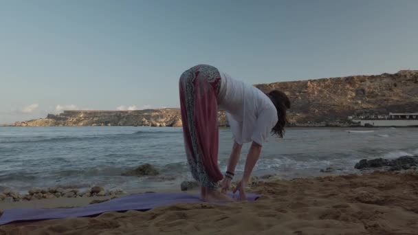 Mujer de 40 años practicando yoga en la playa de arena en la madrugada — Vídeos de Stock