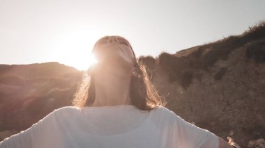 Sabahın erken saatlerinde plajda, uzanmış elleriyle yoga yapan genç bir kadın.