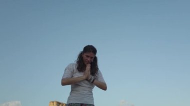 40 'lı yaşlarda bir kadın sabahın erken saatlerinde kumlu sahilde yoga yapıyor.. 