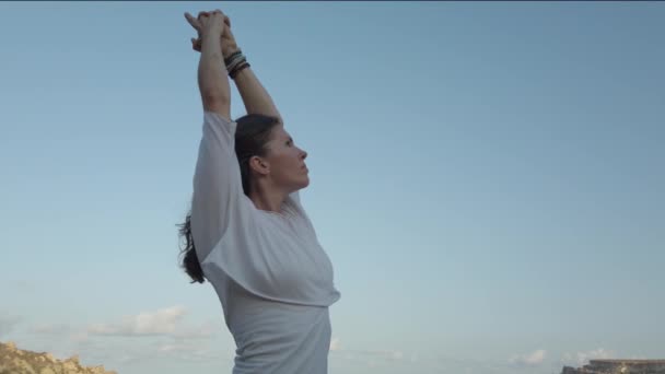 Mujer de 40 años practicando yoga en la playa de arena en la madrugada — Vídeos de Stock