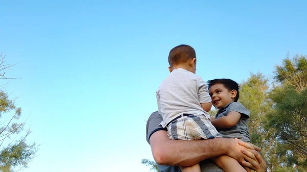 Un jeune père embrassant ses fils dans le parc. Concept de famille heureuse — Photo