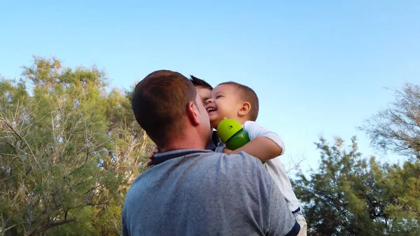 Il giovane padre che abbraccia i suoi figli nel parco. Concetto famiglia felice — Foto Stock