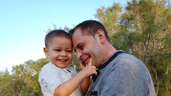 Un giovane padre caucasico che tiene in braccio suo figlio. Bambino toccare il volto di suo padre — Foto Stock