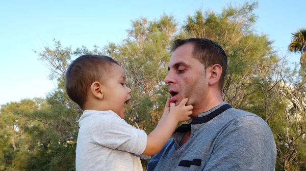 Un giovane padre caucasico che tiene in braccio suo figlio. Bambino toccare il volto di suo padre — Foto Stock