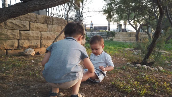 Lindo 4 años de edad ayudando a su hermano a limpiar la rodilla después de que se sintió abajo. Hermanos cuidándose unos a otros —  Fotos de Stock