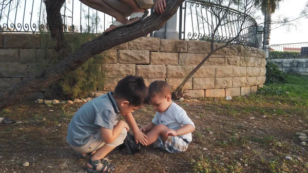 Cute 4 years old helping his brother to clean the knee after he felt down. Siblings taking care of each other — Stock Photo, Image