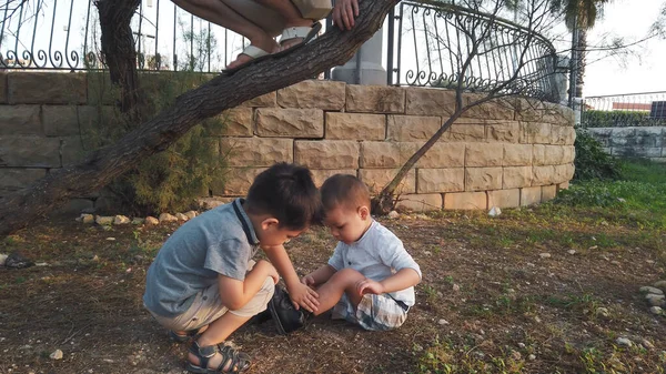 Lindo 4 años de edad ayudando a su hermano a limpiar la rodilla después de que se sintió abajo. Hermanos cuidándose unos a otros — Foto de Stock