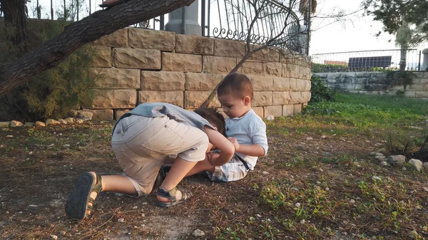 Bedårande 4 år gammal tittar till barnet och kysser hans skadade knä efter att han kände sig nere. Syskon tar hand om varandra — Stockfoto