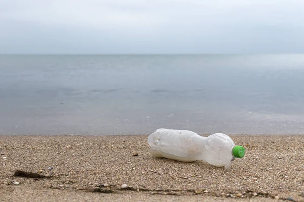 Пустая пластиковая бутылка на песке. Мусор на пляже. Морской берег. Загрязнение окружающей среды Спаси планету. Экологическая проблема. Грязная береговая линия. Природа . — стоковое фото