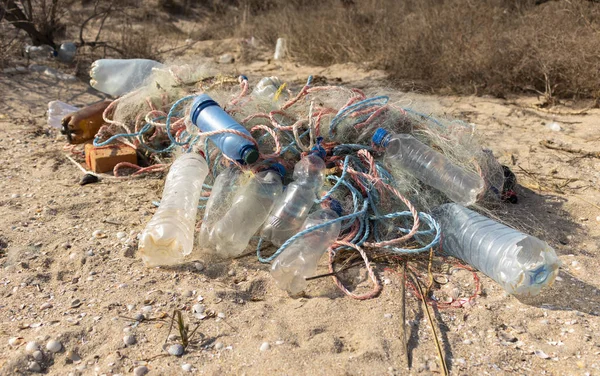 Plastik şişeler ve balık ağlarına kum üzerinde boş. Çöp sahilde. Deniz kirli. Çevre kirliliği. Gezegeni kurtarmak. Ekolojik sorun. Doğa teması.