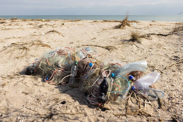 Пустые пластиковые бутылки и рыболовные сети на песке. Мусор на пляже. Грязный морской берег. Загрязнение окружающей среды Спаси планету. Экологическая проблема. Природа . — стоковое фото