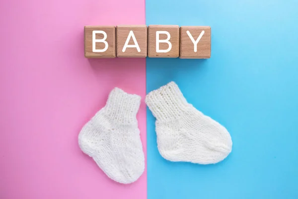 Tahta küplerle ilgili bebek metni ve pembe-mavi arka planda bir çift şirin örgü çorap. Bebeğin cinsiyeti. Erkek ya da kız. Bir çocuk bekliyorum. Yeni doğan kavramı.