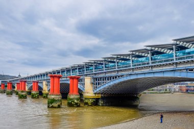 Londra, İngiltere, Ağustos 2018, Thames nehri kıyısında, Blackfriars Demiryolu Köprüsü 'nün oradaki alçak gelgitte duran adam.