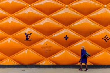 Londra, İngiltere, Mart 2019, Mayfair bölgesinde bir Louis Vuitton mağazası için inşaat alanının önünden geçen bir kadın. 