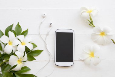 hareket eden telefon ile frangipani aranjman arka plan beyaz tahta üzerinde beyaz çiçek
