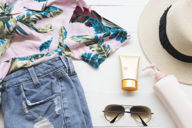 Doğal kozmetik cilt yüz güneş kremi spf50, güneş gözlüğü, kısa kot pantolon, vücut losyonu, şapka ve kadın gömlek relax arka plan ahşap beyaz yaz
