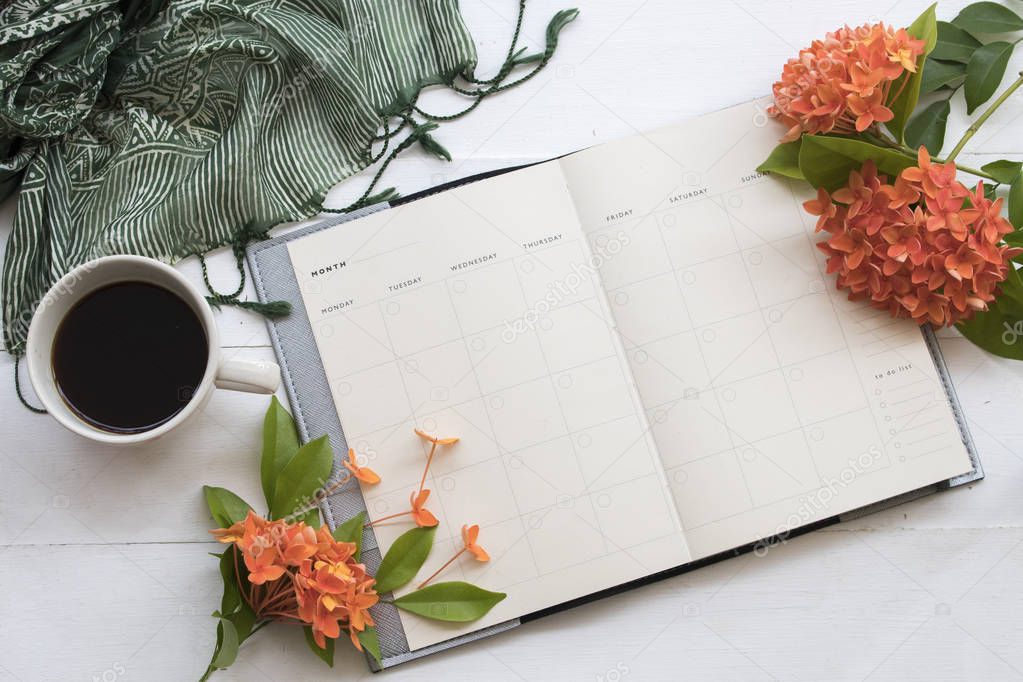 notebook planner for business with orange flower spike flora for asia with green scarf and hot coffee at office desk