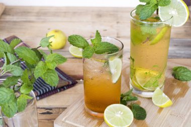 Bitkisel sağlıklı içecekler soğuk limon suyu ve limon çayı sağlık nane yaprağı ve limon dilimi ile ahşap arka plan üzerinde