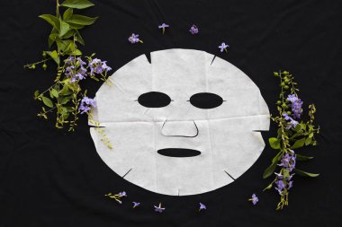 siyah arka plan üzerinde bitkisel çiçek yüzünden cilt için doğal sac maskesi