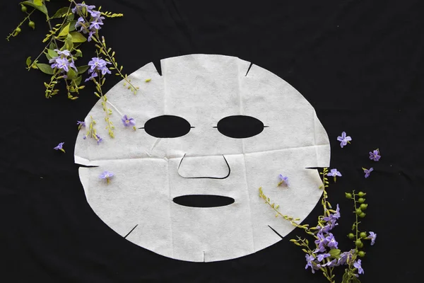 natural sheet mask for skin face from herbal flowers on  background black