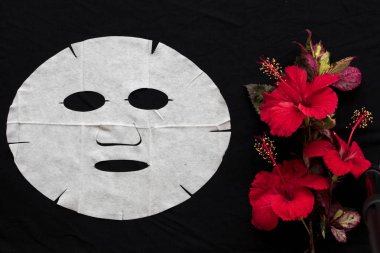 Bitkisel kırmızı çiçekler hibiscus özü yüz maskesi siyah arka plan üzerinde yüzünden cilt için doğal aroma sac maskesi 