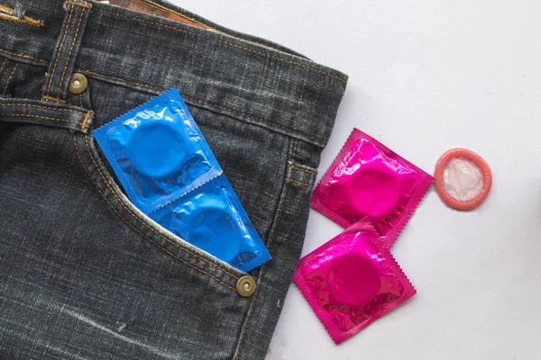避孕套磨损的人保健为性保护疾病概念爱与安全在袋牛仔裤裤子背景白色 — 图库照片