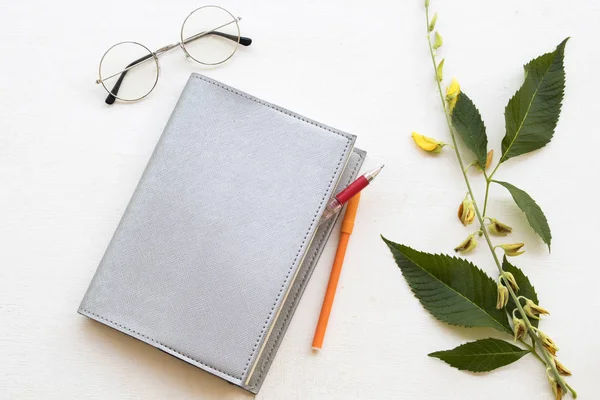 notebook planner for business work at office desk with yellow flower on background white wooden