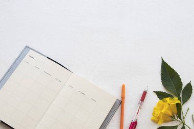 Ofis Masası ahşap arka plan beyaz sarı çiçek ile işyerinde iş için dizüstü bilgisayar planlayıcısı